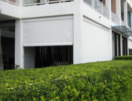 Bottom floor unit balcony with white Zipscreen blinds fully closed and partly closed.